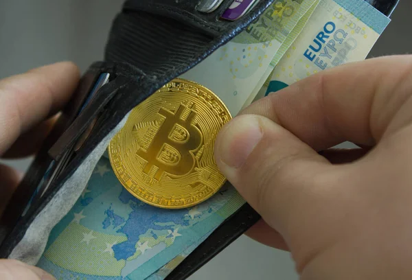 Avro banknotları olan siyah bir cüzdandan bir bitcoin çıkardı.