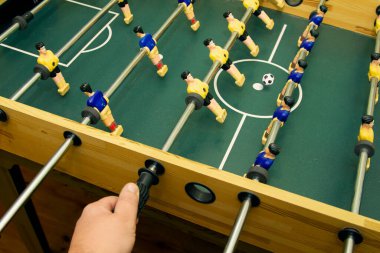 Masa futbolu oynarken oyuncakların kontrol çubuğunu tutan el.
