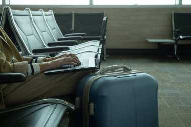 Bavulun yanında dizüstü bilgisayarla çalışan tanınmayan bir kadının ön görüntüsü, odak noktasını seçin ve boşluğu kopyalayın