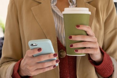 Akıllı telefon ve kahve tutan tanınmayan kadının yatay yakın çekimi, kopyalama alanı