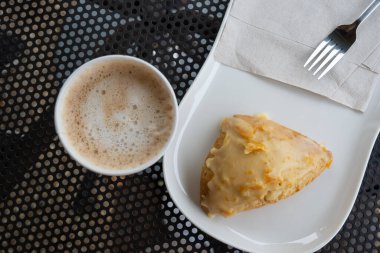 Köpüklü latte ile portakallı çöreğin üst görüntüsü, seçici yaklaşım