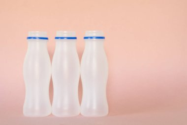 Pembe zemin üzerinde üç plastik şişe ön görünüm, kopyalama alanı, geri dönüşüm konsepti.