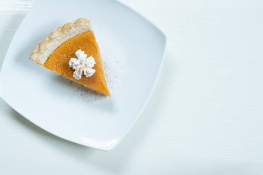 Beyaz arka planda krem şantili ve tarçınlı balkabağı turtasının üst görüntüsü