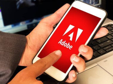 Adobe Mobil Uygulaması akıllı telefon ekranında, elinde dizüstü bilgisayarla açıldı. Editörlük kavramı arkaplanı