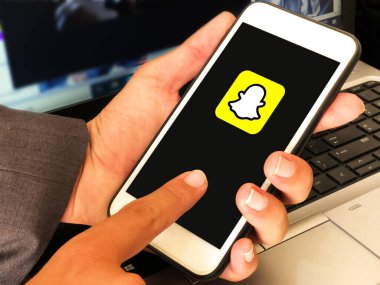 Snapchat Logosu, Mobil Ekranda dizüstü bilgisayarın önünde duran adamla birlikte görünüyor. Sosyal medya arka planının editör konsepti