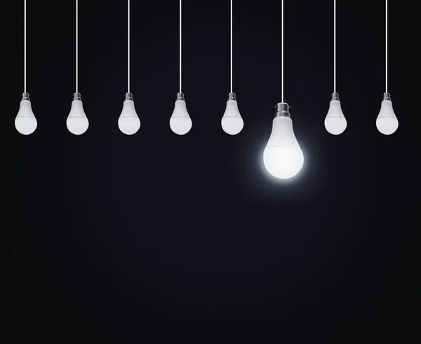 Hanging Bulbs in Line with One Glowing Big bulb Among All on the dark background. Concept Base Abstract Minimal dark backdrop with light one on bulb.