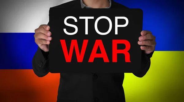 Young Man Holding Stop War Cardboard in front of Two Flags. Say no to war concept background