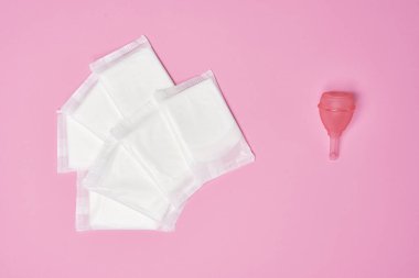 paketli pamuklu hijyenik peçete, pembe arka planda silikon pembe adet bardağı.