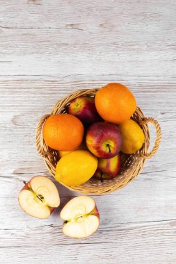 Tahta bir masada sepetteki meyveler. Elmalar, portakallar, sepette limonlar. Düz yatıyordu.