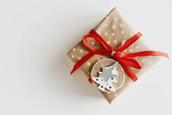圣诞礼品盒用波尔卡圆点牛皮纸包裹 上面装饰着红丝带和木制圣诞树及星形装饰品 环保礼品包装理念 — 图库照片