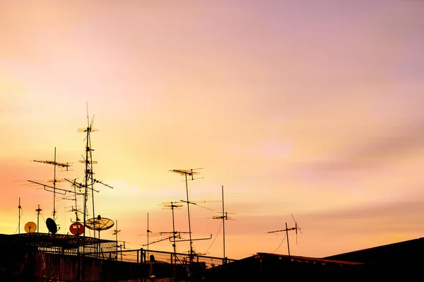 electrical transmission antennas at house roof on sunset background