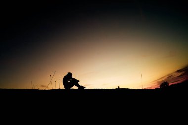 Bir adamın silueti, kalp kırıklığı ve işsizlik yüzünden yalnız başına oturur. Umutsuz ve işsiz konsepti