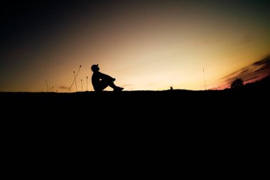 Bir adamın silueti, kalp kırıklığı ve işsizlik yüzünden yalnız başına oturur. Umutsuz ve işsiz konsepti