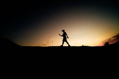 Siluet Adam güzel bir ışık akşamında kırsal alanda cep telefonu kullanıyor..