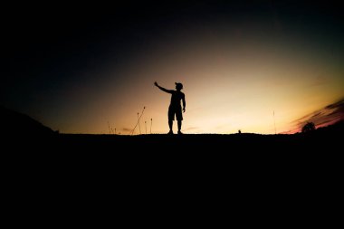 Siluet Adam güzel bir ışık akşamında kırsal alanda cep telefonu kullanıyor..