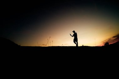 Siluet Adam güzel bir ışık akşamında kırsal alanda cep telefonu kullanıyor..