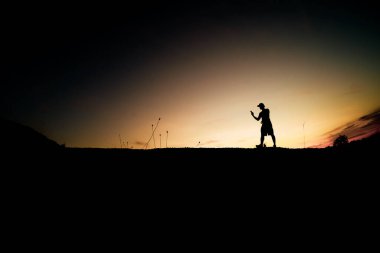 Siluet Adam güzel bir ışık akşamında kırsal alanda cep telefonu kullanıyor..