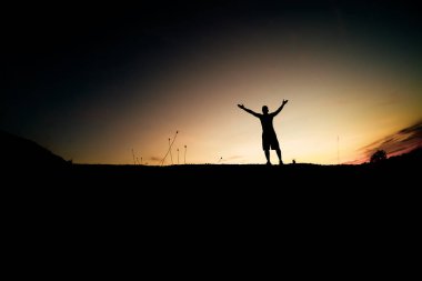 Bir adamın silueti ellerini mutluluktan kaldırır..