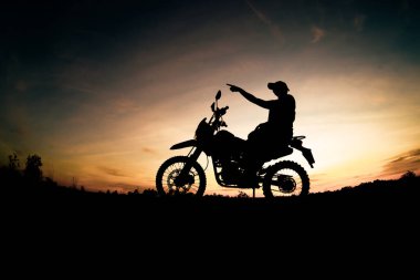 Erkek silueti ve motosiklet turu. Akşamları rahatlamak için dağlara park et.
