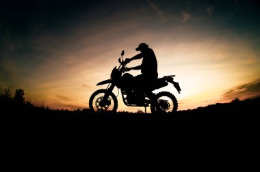 Erkek silueti ve motosiklet turu. Akşamları rahatlamak için dağlara park et.