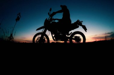 Motosikletle seyahat eden adamların siluetleri.