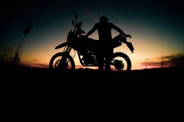 Motosikletle seyahat eden adamların siluetleri.