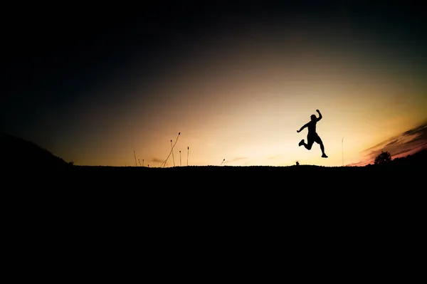 喜びで飛び回る男性のシルエット 美しい光の中での自由夜 — ストック写真