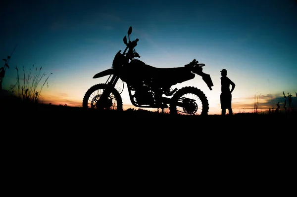 日落背景下骑摩托车旅行的人的轮廓 — 图库照片