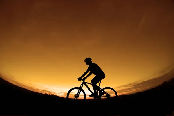 석양을 배경으로 자전거를 자전거 운전자의 실루엣 — 스톡 사진
