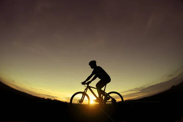 석양을 배경으로 자전거를 자전거 운전자의 실루엣 — 스톡 사진