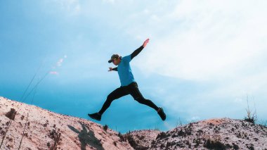 Mavi arkaplanda zıplayan erkek koşucu, boşluğu kopyala