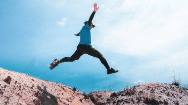 Mavi arkaplanda zıplayan erkek koşucu, boşluğu kopyala