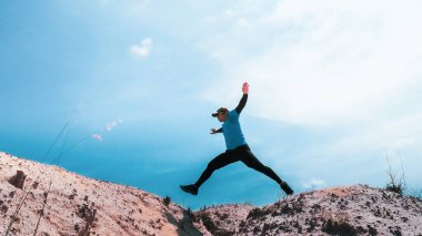 Mavi arkaplanda zıplayan erkek koşucu, boşluğu kopyala