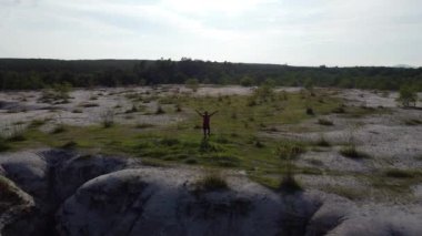 Kırmızı spor giyim giymiş Asyalı bir adam yüksek bir dağda koşuyor.