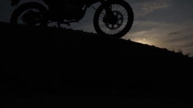 Akşamları bir motokros motosikleti silueti. Macera Gezgini konsepti