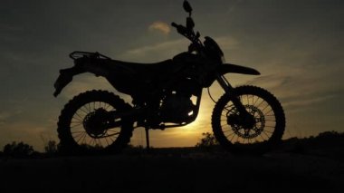 Akşamları bir motokros motosikleti silueti. Macera Gezgini konsepti
