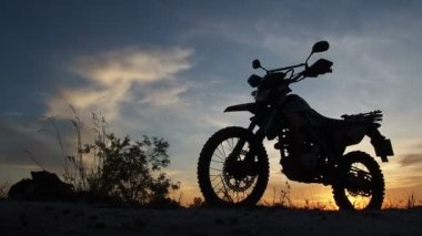 Akşamları bir motokros motosikleti silueti. Macera Gezgini konsepti