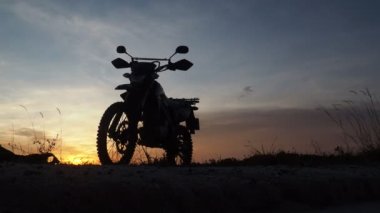 Akşamları bir motokros motosikleti silueti. Macera Gezgini konsepti