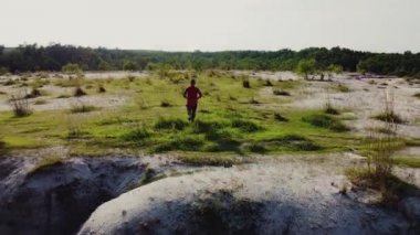 Kırmızı spor giyim giymiş Asyalı bir adam yüksek bir dağda koşuyor.