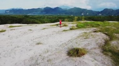 Kırmızı spor giysili Asyalı adam dağlarda koşuyor ve antrenman yapıyor.