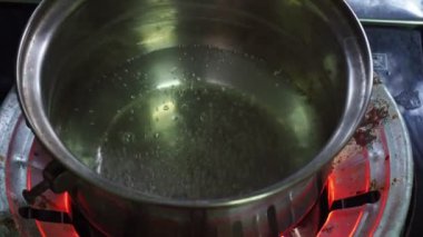 Gaz ocağı mutfaktaki bir tencerede kaynar su kaynıyor.