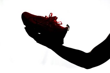 Beyaz arka planda koşan bir ayakkabıyı tutan bir adamın silueti. Koşu ayakkabısı almak ve egzersiz yapmak için fikirler.