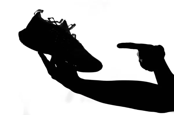 一个人的手在白色背景上拿着跑鞋的轮廓 购买跑鞋和运动的建议 — 图库照片