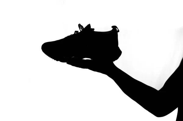 Beyaz Arka Planda Koşan Bir Ayakkabıyı Tutan Bir Adamın Silueti — Stok fotoğraf