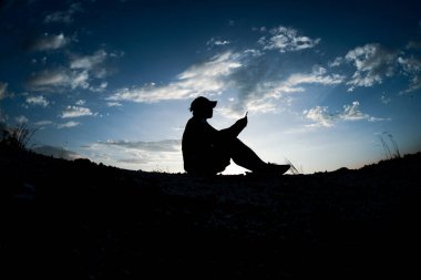 Gün batımında telefonu olan bir adamın silueti.