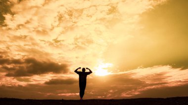 Erkeklerin siluetleri son derece mutlu. Erkek silueti, ellerini neşe ve özgürlükle kaldırıyordu. özgürlük kavramı