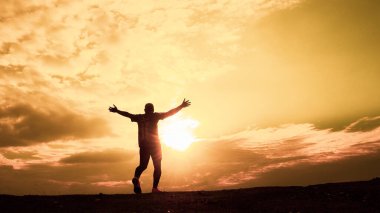 Erkeklerin siluetleri son derece mutlu. Erkek silueti, ellerini neşe ve özgürlükle kaldırıyordu. özgürlük kavramı