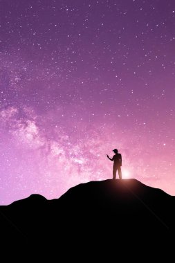 Samanyolu ile gece manzarası. Dağda kollarını kaldırmış genç bir adamın silueti. Güzel Evren. Seyahat arkaplanı