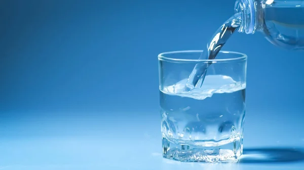 工作室拍摄干净的饮用水倒入玻璃和天然蓝色背景 健康饮水概念 — 图库照片