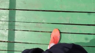 Yeşil, ahşap köprüde erkek bacaklarının yakın çekimi.